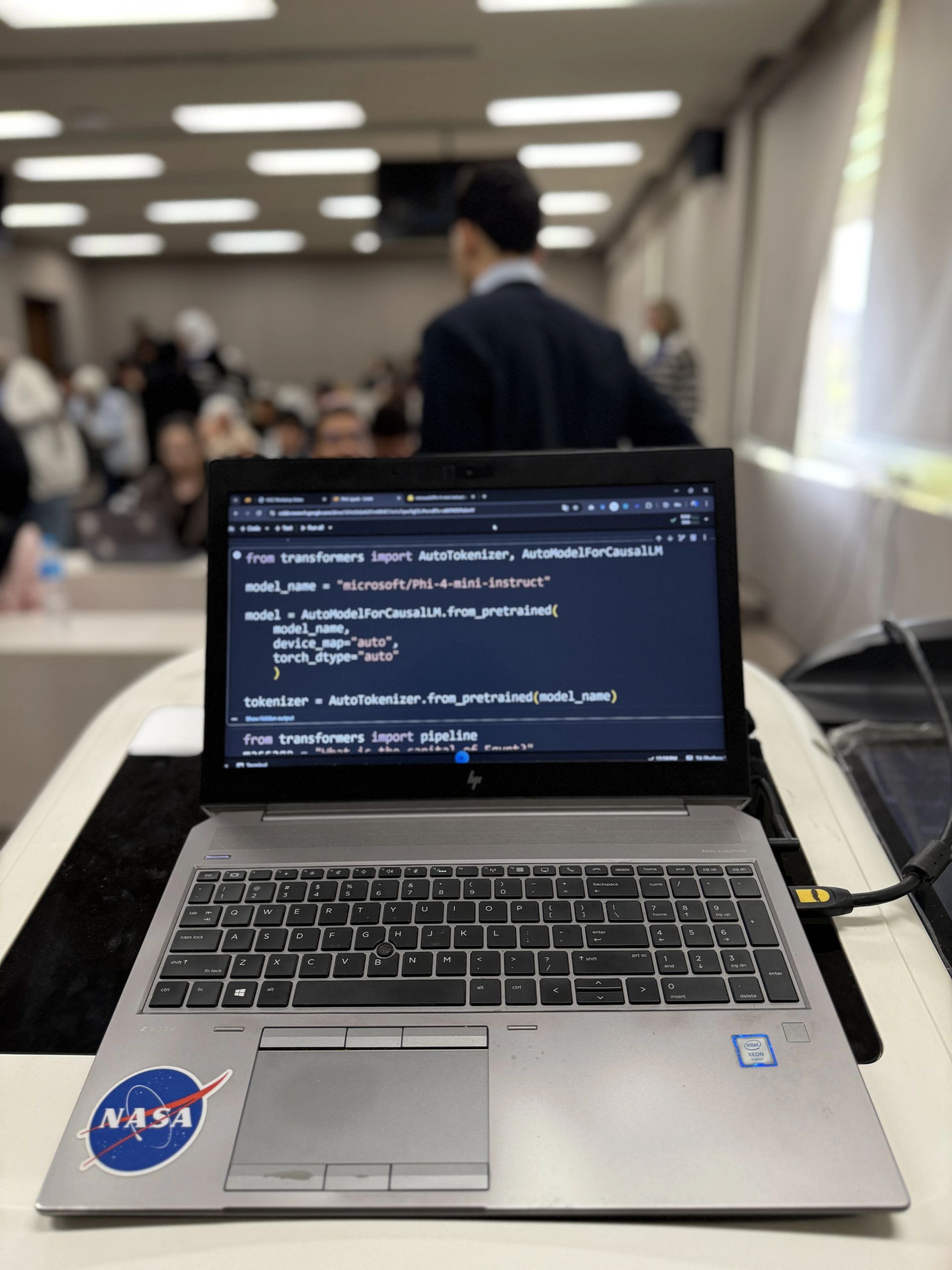Introduction to Large Language Models: Laptop code editor students outof focus behind the laptop