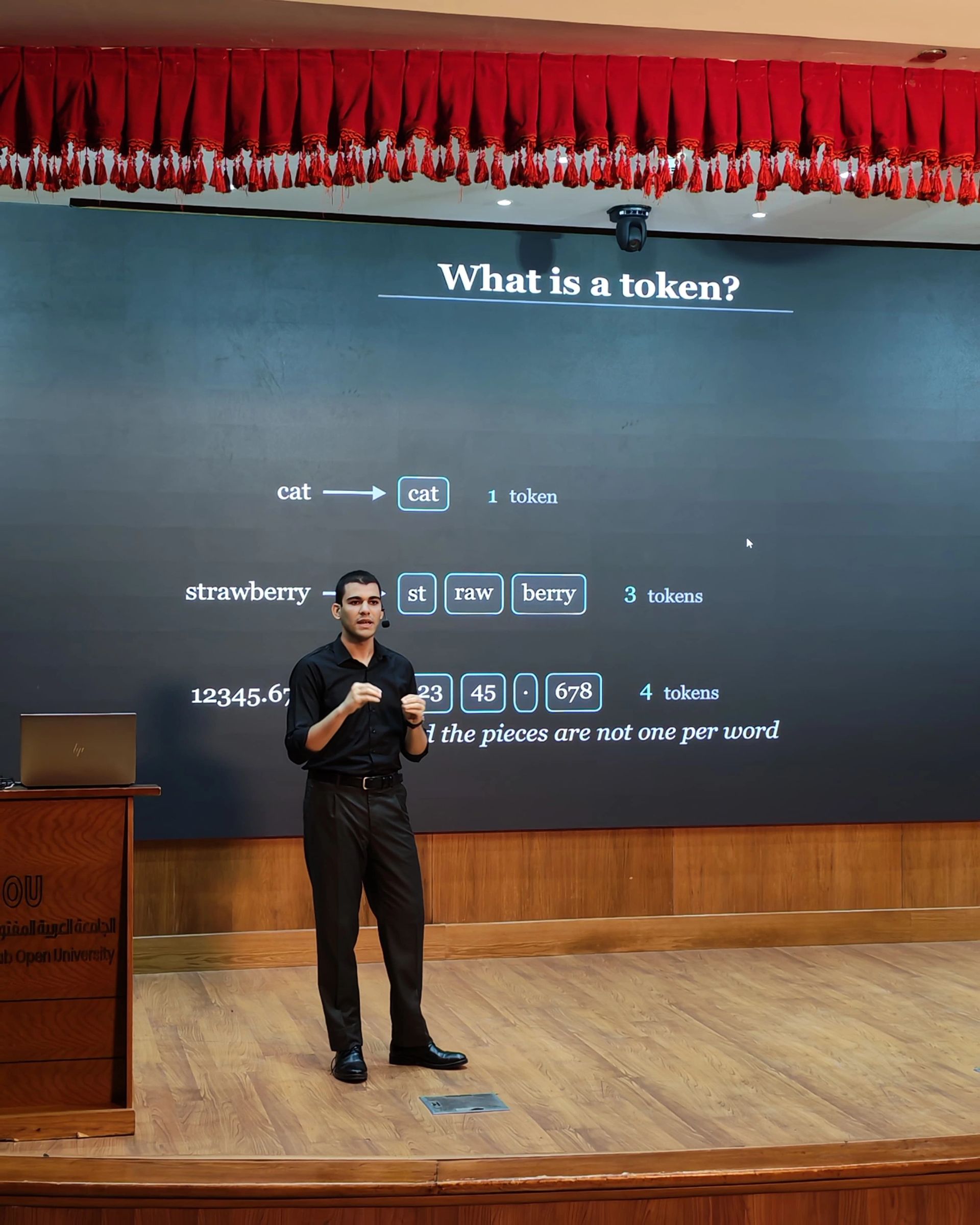 LLM Engineering Bootcamp: From Foundations to Deployment: Moaz on stage explaining a token